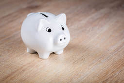 White 'piggy bank' sitting on a wooden table