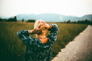 Woman in blue standing looking at a field of grass.